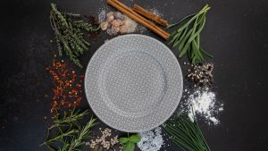 a plate surrounded by spices and herbs