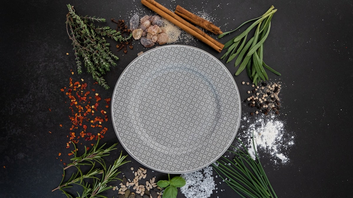 a plate surrounded by spices and herbs